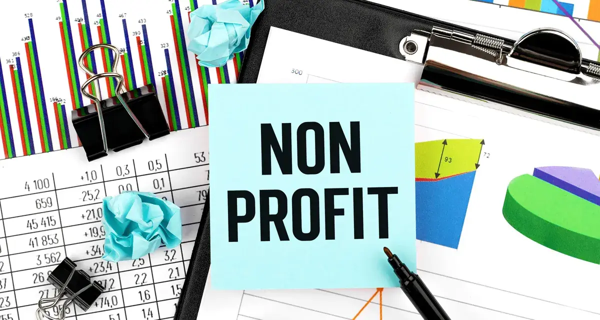 Analyzing financial reports for nonprofits. The image shows charts, graphs, and a sticky note with "NON PROFIT" written on it.