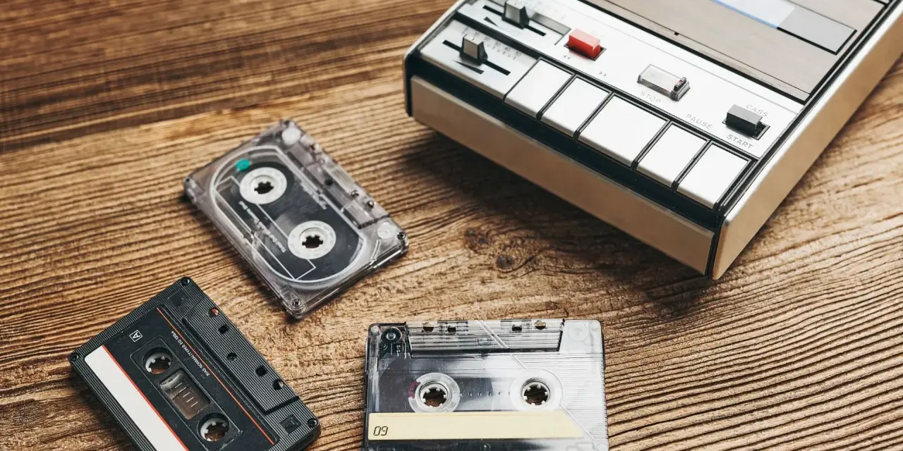 Kasety magnetofonowe i odtwarzacz leżą na drewnianym blacie. Zastanawiasz się, ile warte są kasety magnetofonowe?