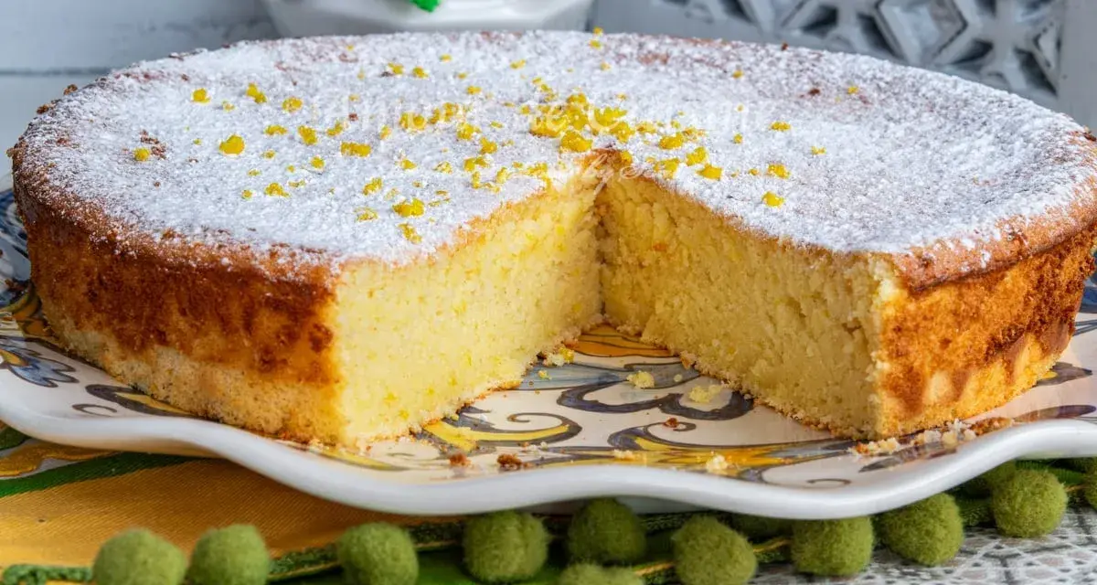 Un moelleux au citron, saupoudré de sucre glace et de zestes, attend d'être dégusté. Sa texture aérienne promet un délice.