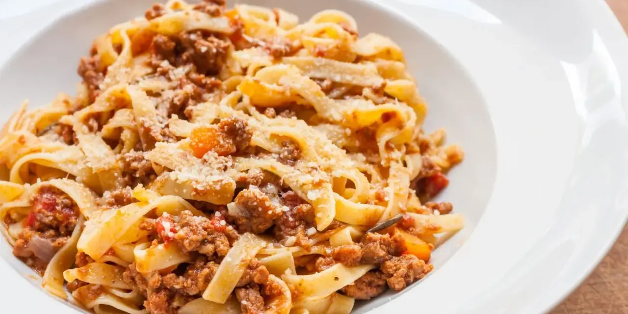 Tagliatelle z bogatym, mięsnym sosem bolońskim, posypane parmezanem. Pyszne danie, które zadowoli każdego miłośnika włoskiej kuchni.