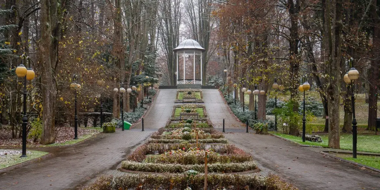Polanica Zdrój co warto zobaczyć: jesienny park z altaną i alejkami, ozdobnymi rabatami i latarniami.