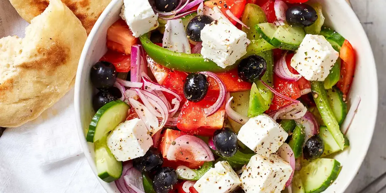 Frischer griechischer Salat mit Tomaten, Gurken, Oliven, roter Zwiebel und Feta-Käse, serviert mit Fladenbrot.
