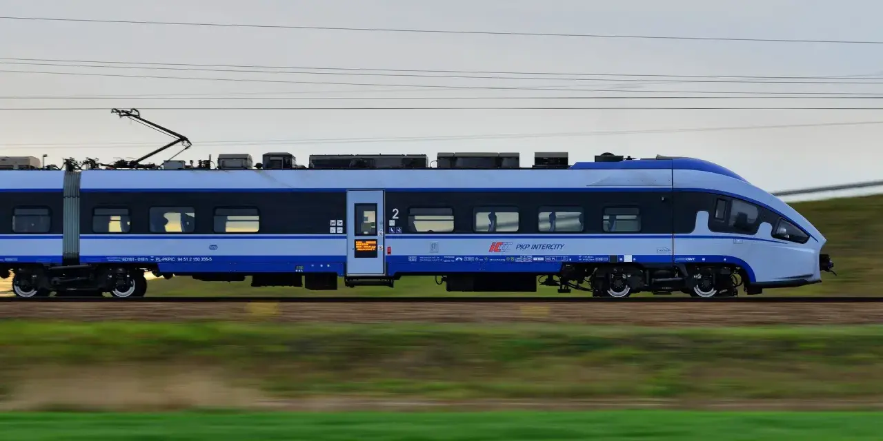 Pociąg PKP Intercity w ruchu, z widocznymi oknami i logo przewoźnika.