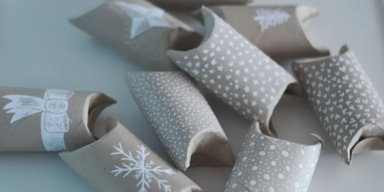 En adventskalender av toarullar, dekorerade med vita julmotiv som snöflingor och stjärnor. Perfekt för att skapa egna små överraskningar.