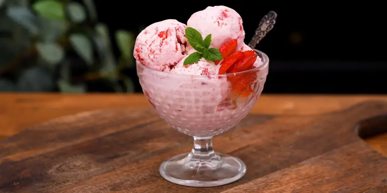 Ljuvlig jordgubbsglass utan glassmaskin i en skål, dekorerad med färska jordgubbar och mynta. Perfekt sommardessert!