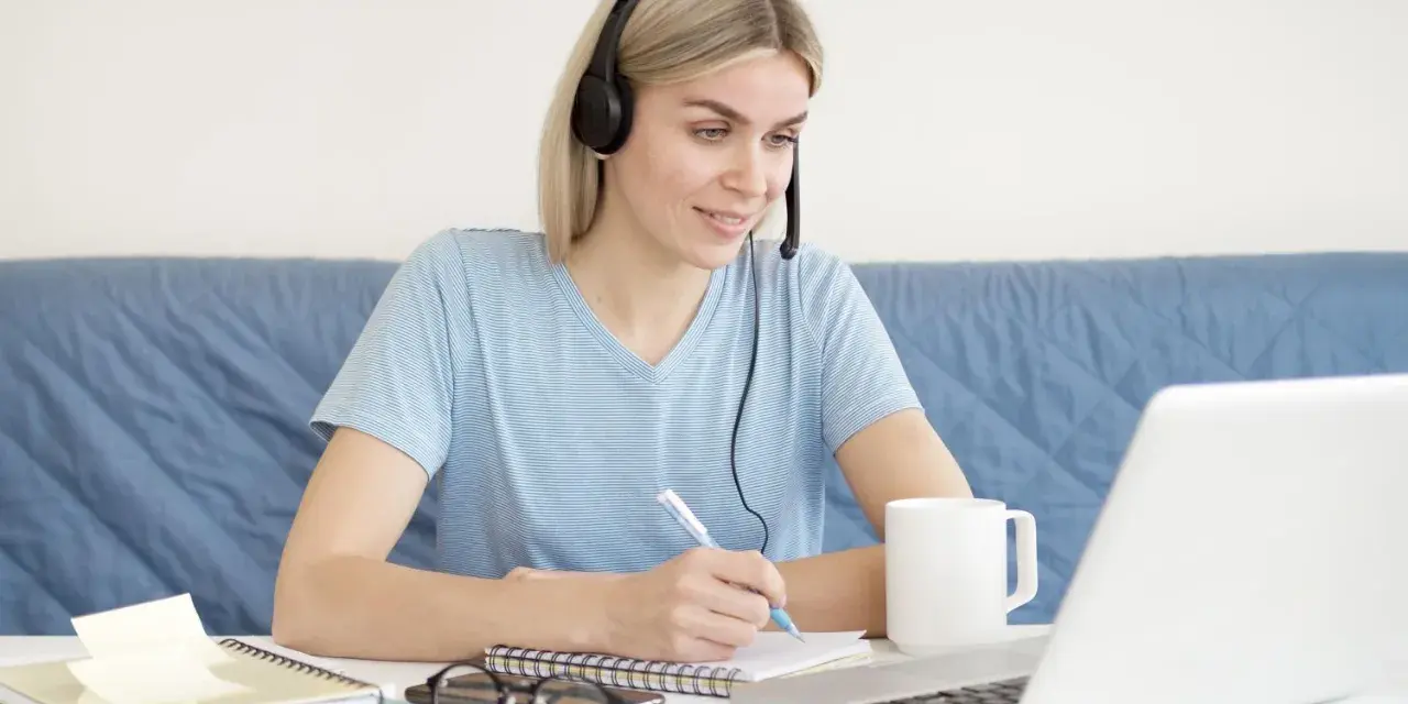 Pielęgniarka słucha wykładu na słuchawkach i notuje. Dostępne są darmowe kursy online dla pielęgniarek.