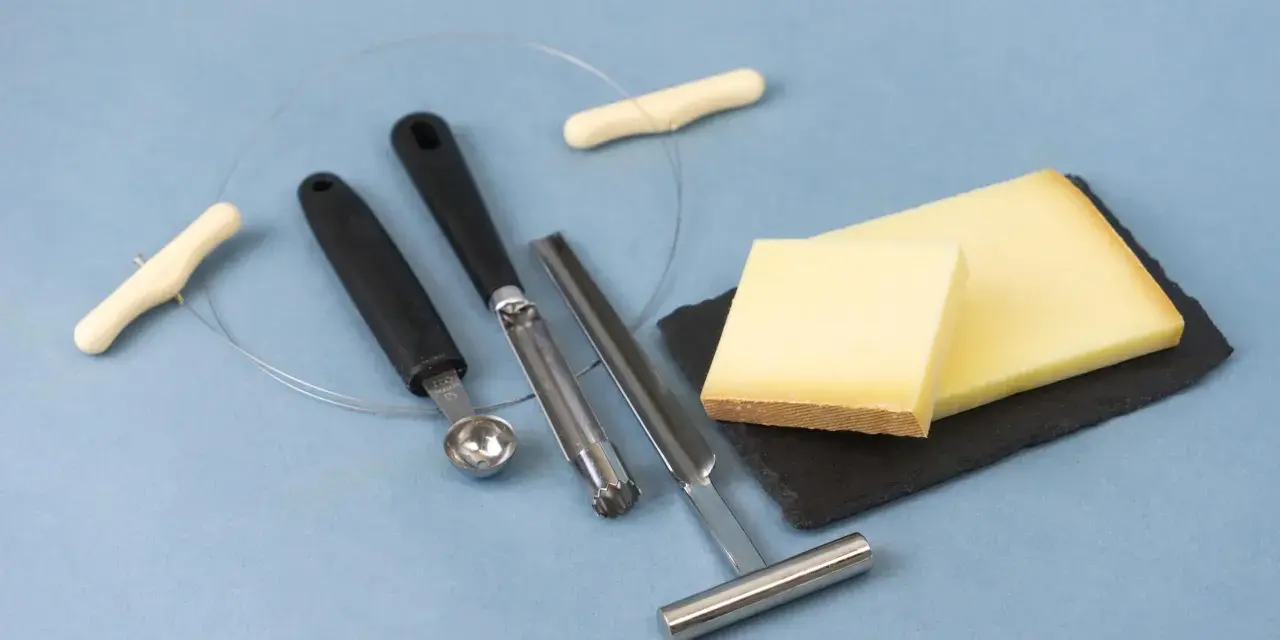 Des morceaux de fromage, des outils pour le découper et une ficelle. L'origine du fromage la dent du chat est un mystère savoureux.