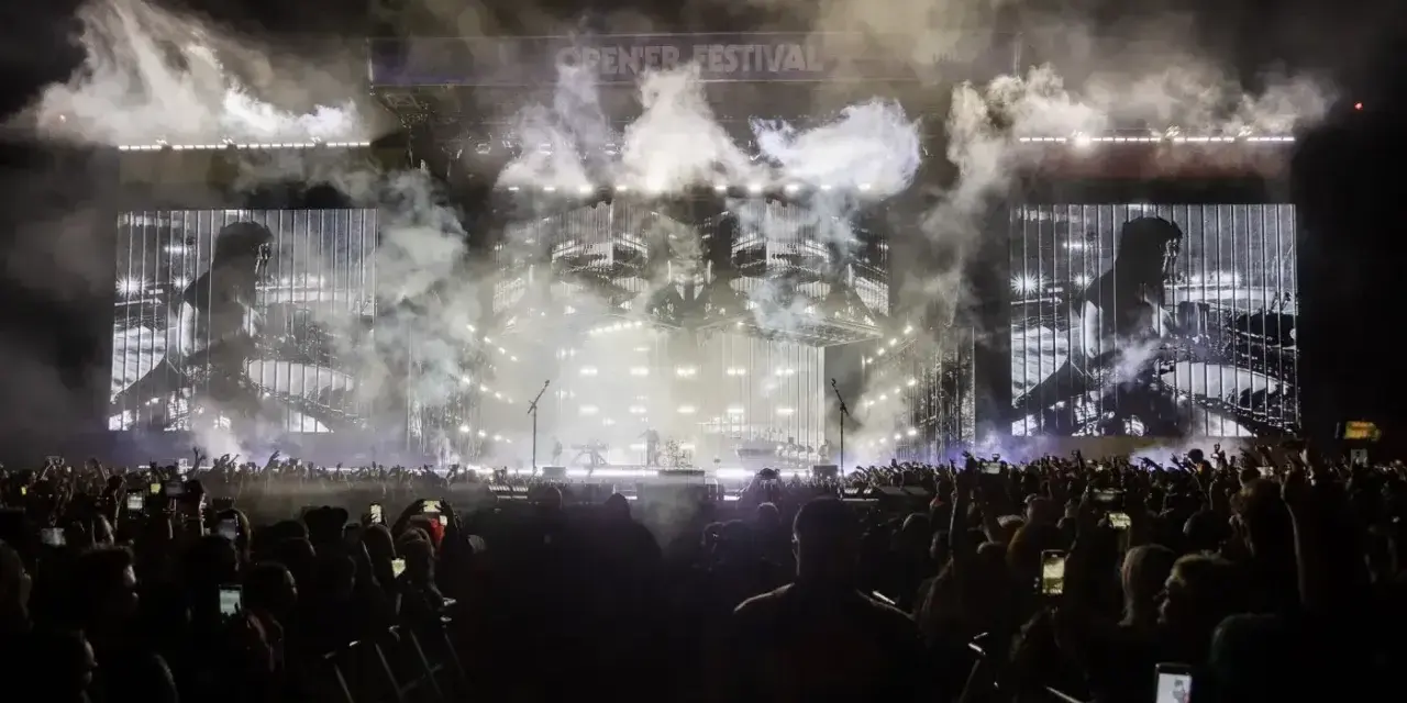 Koncert Linkin Park na Opener Festival. Tłum ludzi z telefonami, dym i światła na scenie.