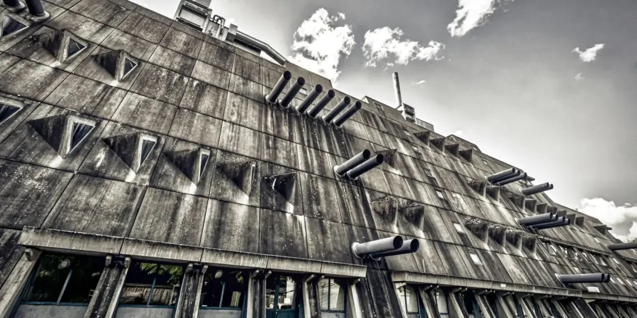 Betonriese im **Brutalismus Berlin**: Eine Fassade mit dreieckigen Fenstern und Rohren, die wie Kanonen aussehen.