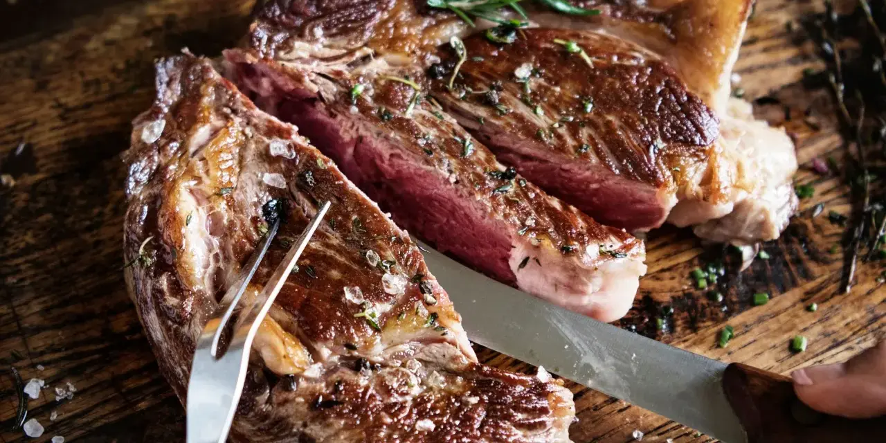 Una succulenta bistecca di manzo, tagliata al sangue, condita con sale grosso e rosmarino, pronta per essere gustata.
