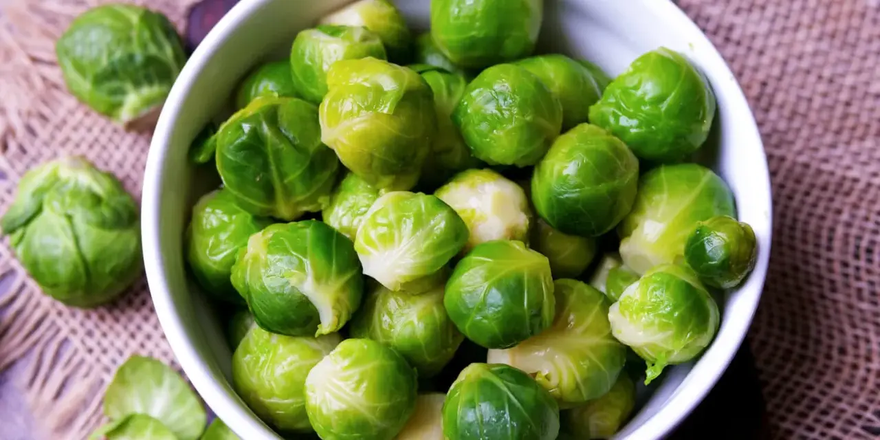 Frischer Rosenkohl in einer Schüssel. Die Frage "wie lange muss rosenkohl kochen" beschäftigt viele Hobbyköche.