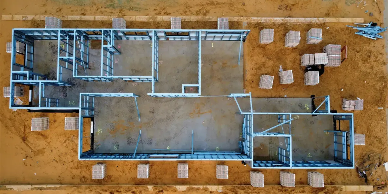 Estructura metálica de una casa en construcción. Se aprecian materiales apilados, listos para el montaje. El precio de hacer un sótano puede variar.