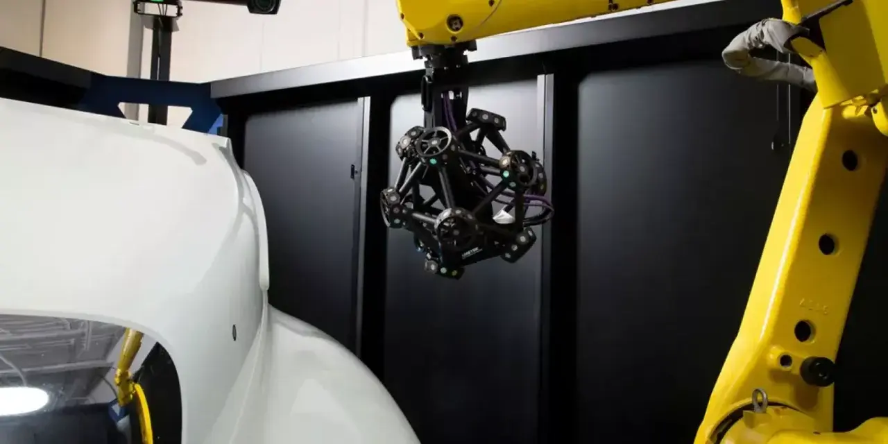 Robotyka i zaawansowany skaner optyczny badają kształt białego elementu, prawdopodobnie części samochodu.