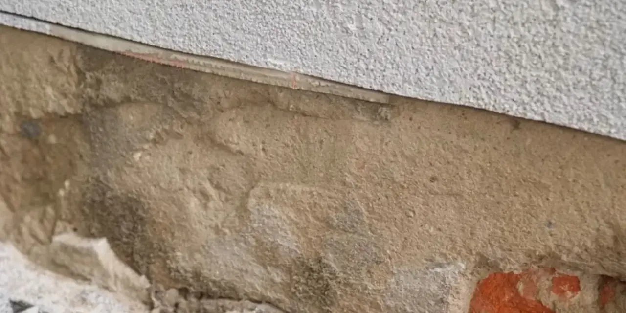 Fragment ściany z widoczną warstwą izolacji i miejscem na iniekcję.
