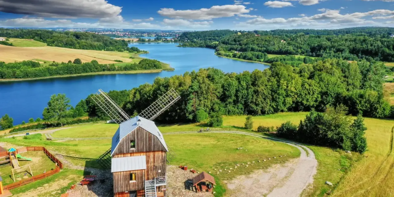 Wiatrak na tle jeziora i lasów. Tak właśnie wyglądają Kaszuby, malowniczy region pełen zieleni i wody.
