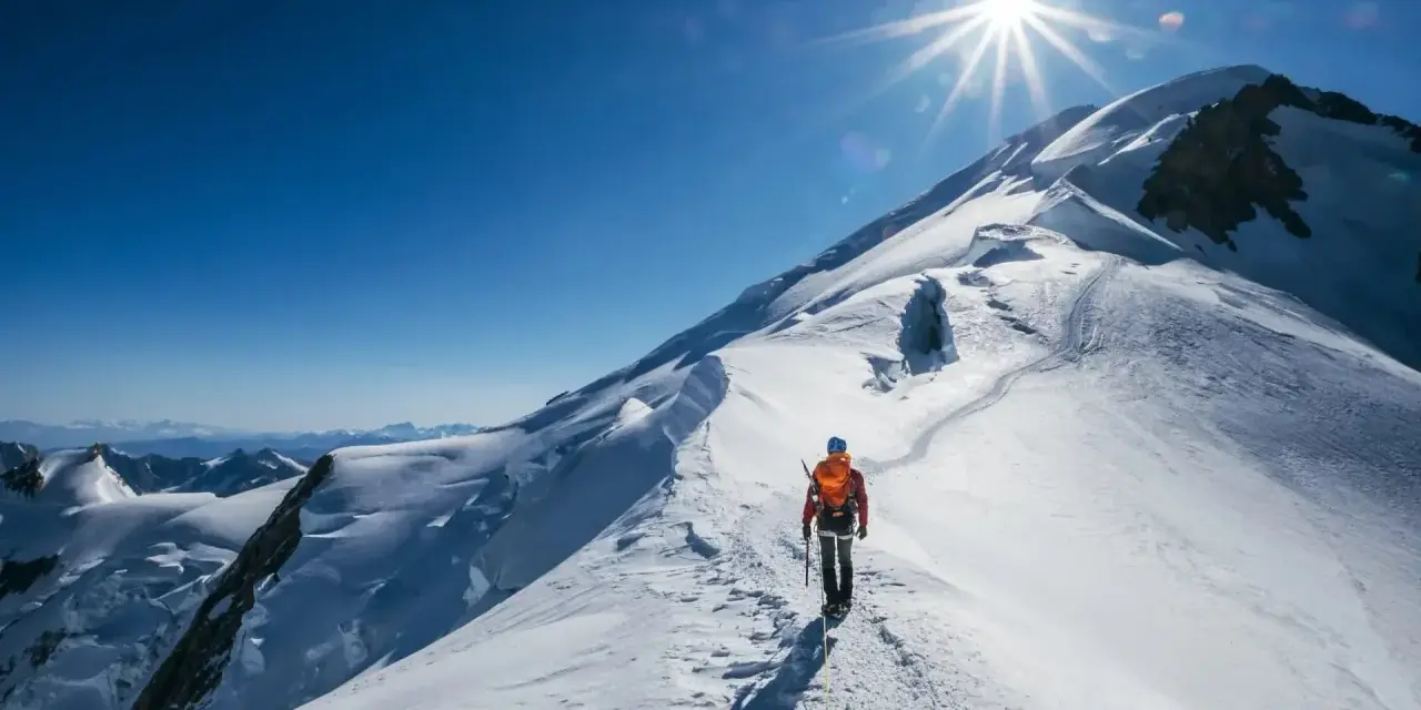 Bergsteiger auf dem Weg zum Gipfel des Mont Blanc. Die Sonne strahlt vom klaren blauen Himmel.