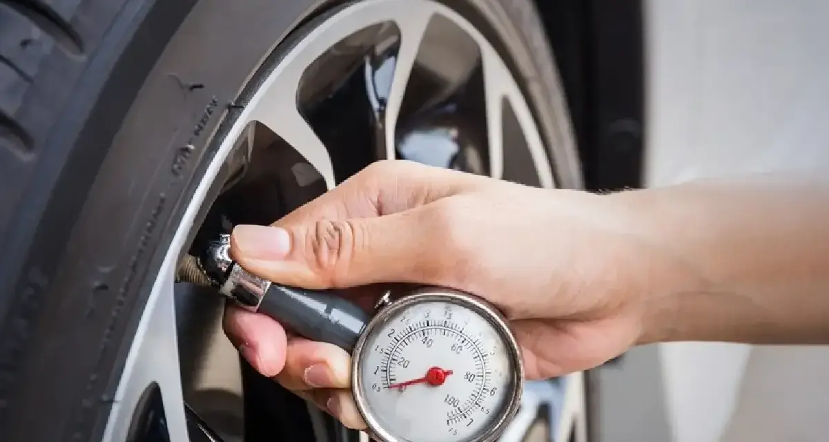 Controllo della pressione gomme 185/65 r15 con manometro. La mano tiene lo strumento attaccato alla valvola.