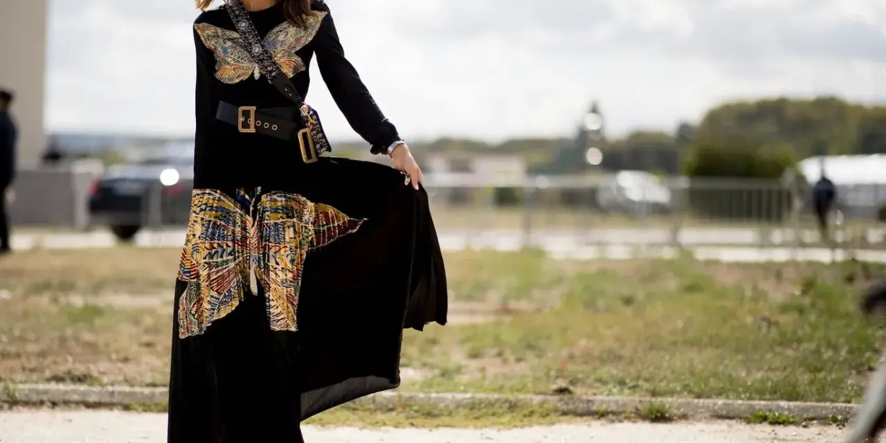 Mujer con vestido largo negro con estampado de mariposas, cinturón ancho y botines. Un ejemplo de como llevar un vestido largo informal con estilo.