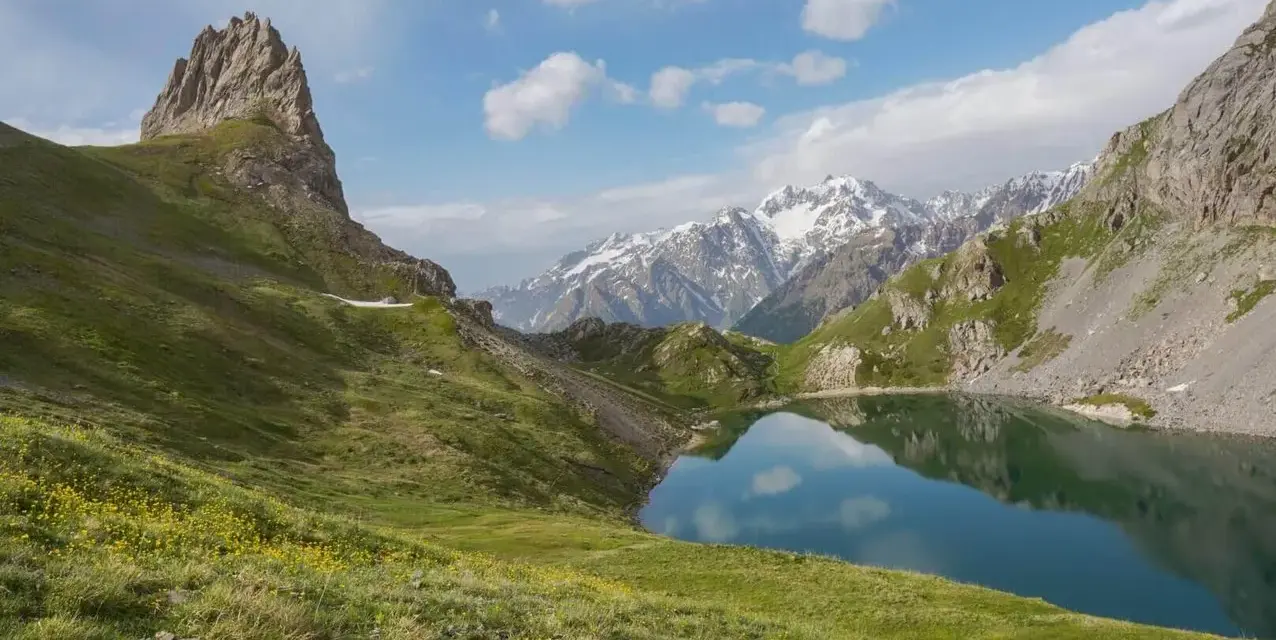 Magnifique lac alpin reflétant les montagnes enneigées, idéal pour une randonnée près de Briançon.