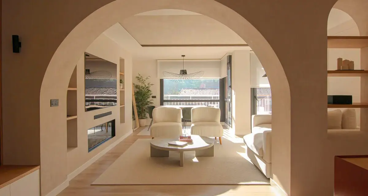 Amplio salón con entrada recibidor integrado. Dos sillones blancos, mesa de centro y sofá invitan a la relajación.