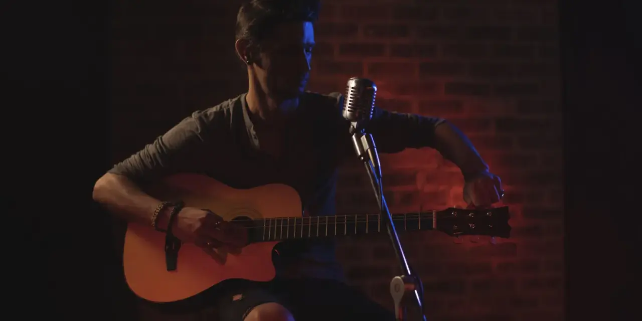 Mann stimmt seine Gitarre, bereit für die Aufnahme. Die Gitarren-Tunings sind entscheidend für den perfekten Klang.