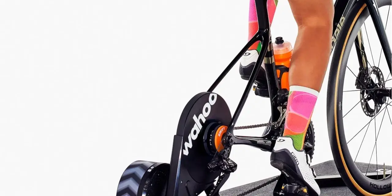 Cyclist training indoors on a bike with a Wahoo trainer, experiencing adjustable bike resistance for a challenging workout.
