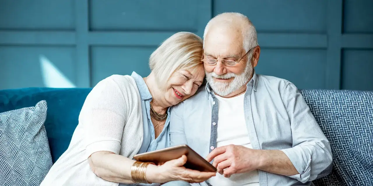 Uśmiechnięta para seniorów przegląda tablet. Szukają informacji: operacja zaćmy NFZ gdzie najszybciej, by odzyskać jasność widzenia.