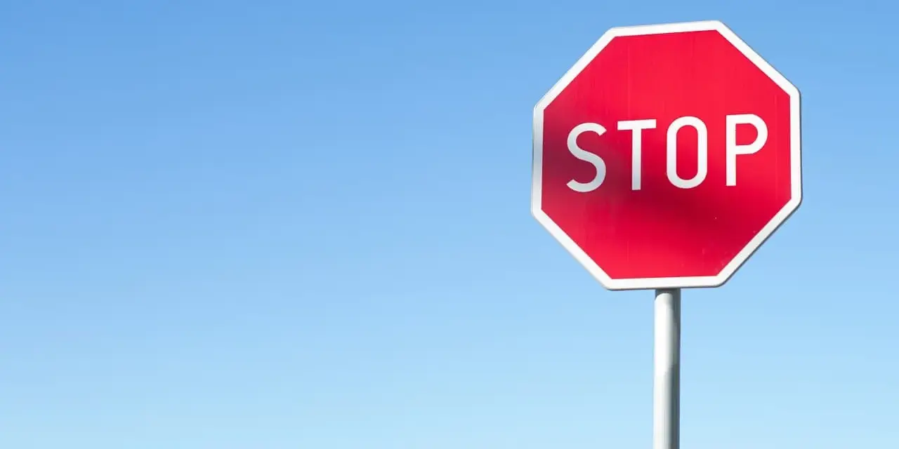 Czerwony znak STOP na tle błękitnego nieba. Uważaj, by nie dostać mandatu za stop!
