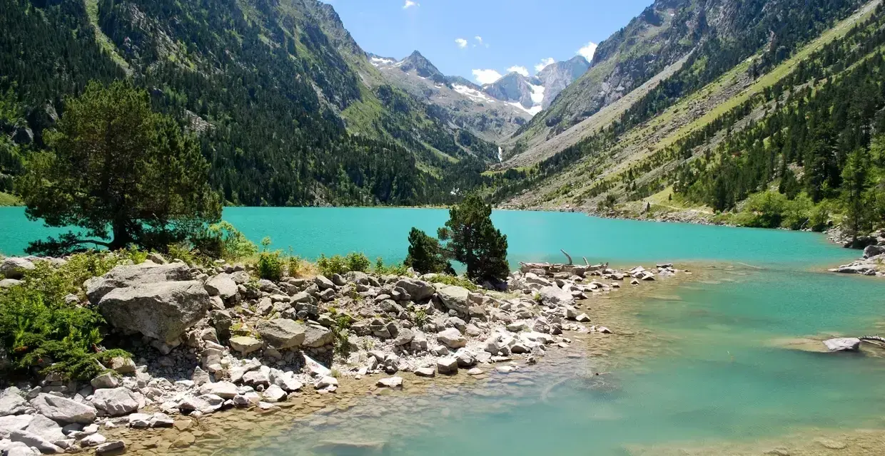 Un lac turquoise aux reflets émeraude, niché au cœur d'une vallée verdoyante des Pyrénées. Un paysage de carte postale, invitant à la contemplation.