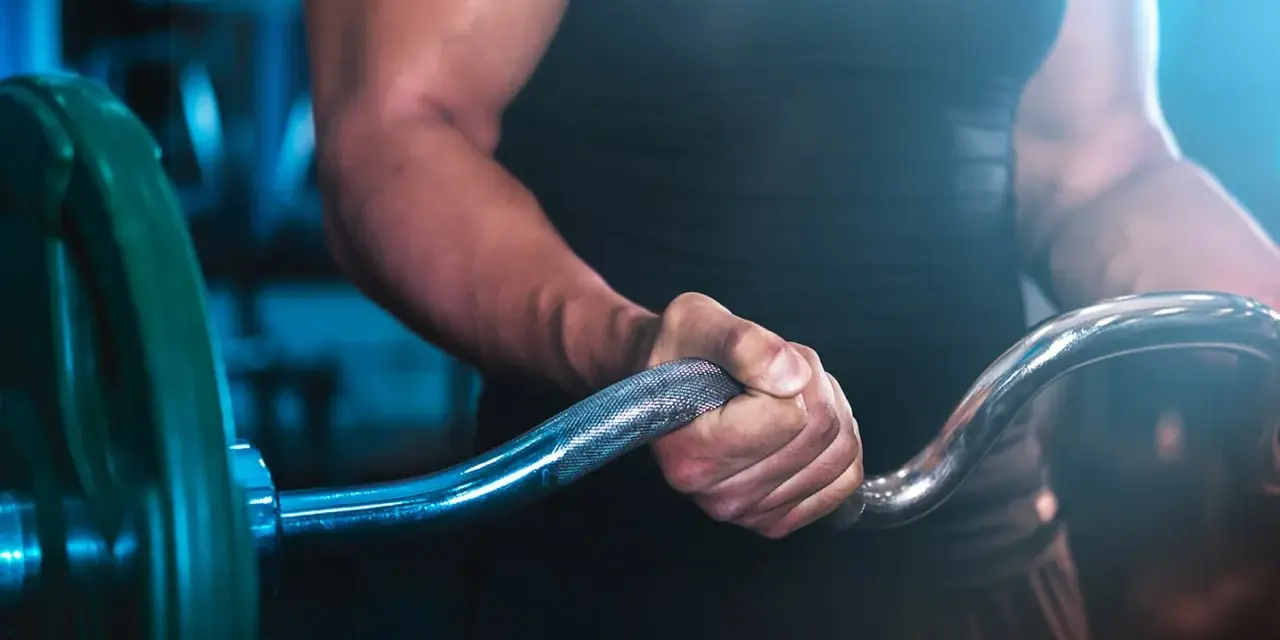Muskulös arm som greppar skivstång i ett superset gym.