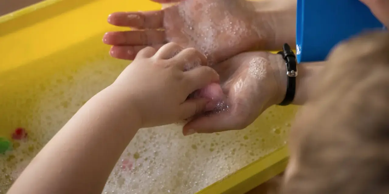 Dziecko myje ręce w wannie z pianą. Może to być jeden z objawów zaburzeń czucia głębokiego u dzieci.