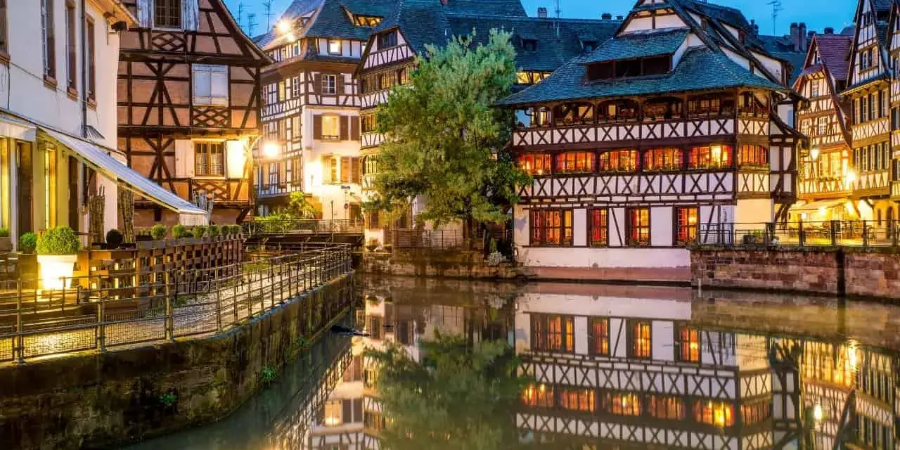 Casas con entramado de madera reflejadas en un canal, un ejemplo de la calidad de vida en Francia.