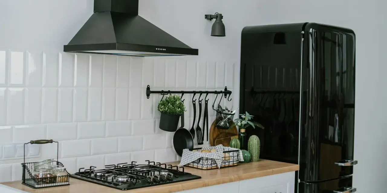 A clean vent hood filter is crucial for kitchen safety and efficiency. This image shows a modern kitchen with a black vent hood over a gas stove.