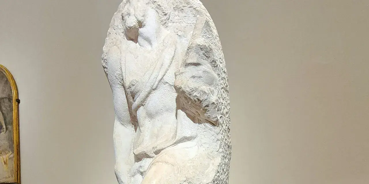 Niedokończony posąg Michała Anioła, ukazujący fragment ludzkiego ciała wyrzeźbionego z marmuru.