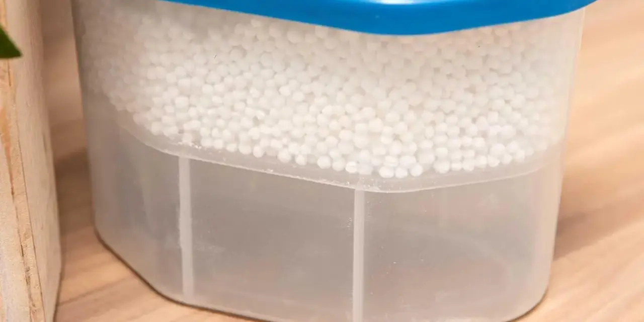 Luftentfeuchter Granulat wird hart, wenn es Feuchtigkeit aufnimmt. Der Behälter zeigt, wie das Granulat die Luft trocknet und sich unten Wasser sammelt.