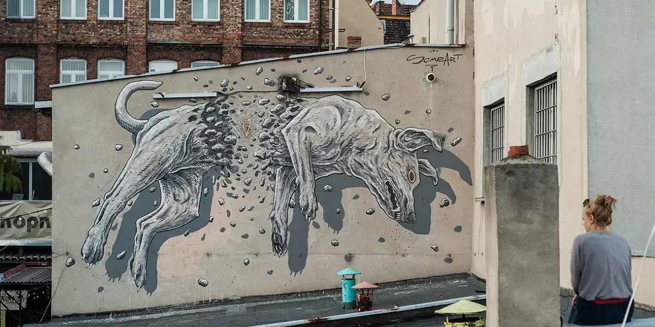 Niesamowite street art graffiti przedstawiające psa rozpadającego się na kamienie. Dzieło sztuki miejskiej na ścianie kamienicy.