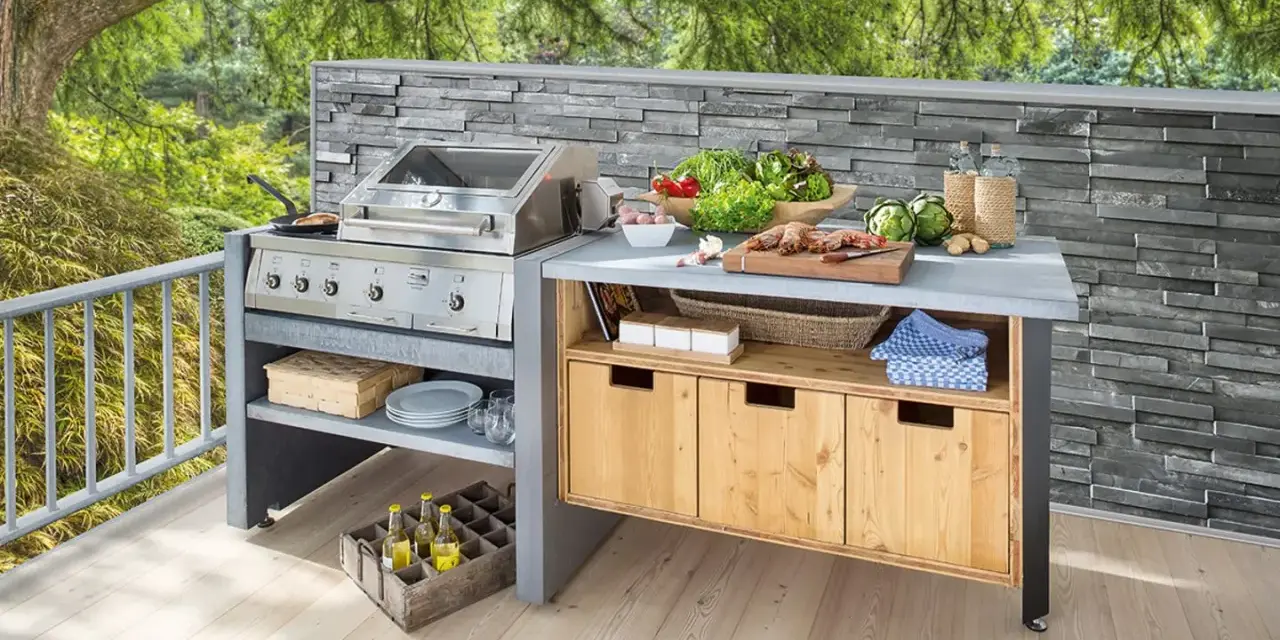 Moderne Grillecke im Garten mit Edelstahlgrill, Arbeitsplatte, Holzschränken und frischen Zutaten. Tolle Garten Ideen für Grillmeister.