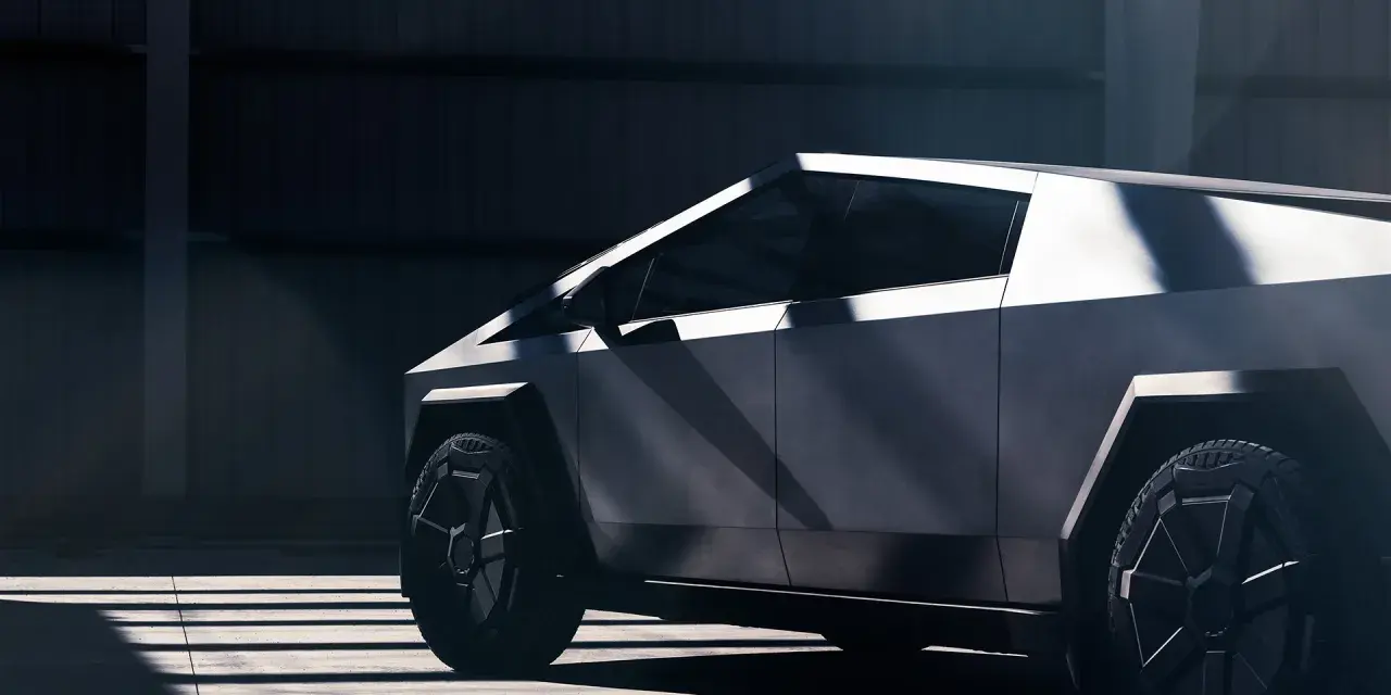 Tesla Cybertruck w ciemnym wnętrzu, widok z boku, podkreślony przez światło i cień.