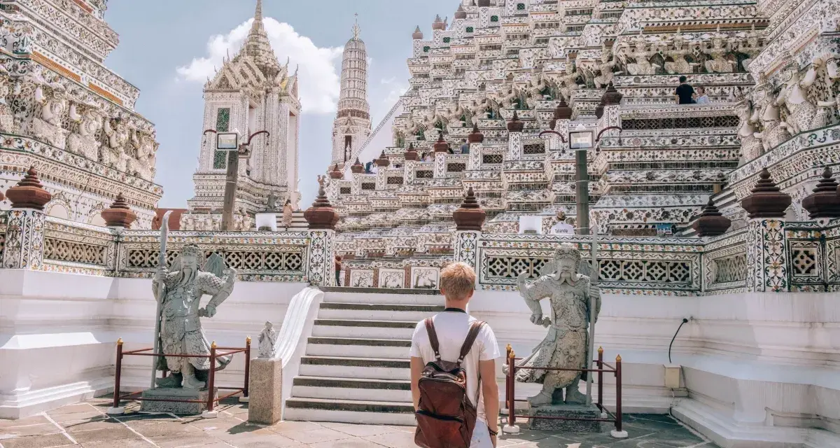 Młody turysta z plecakiem podziwia majestatyczną świątynię Wat Arun w Bangkoku. Czy Bangkok jest bezpieczny? Tak, zwłaszcza w takich pięknych i spokojnych miejscach.
