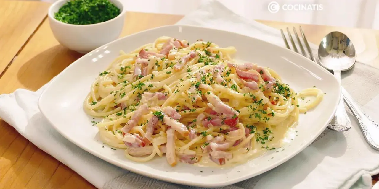 Espaguetis con nata, cubiertos de trocitos de bacon y perejil picado. Un plato cremoso y delicioso.