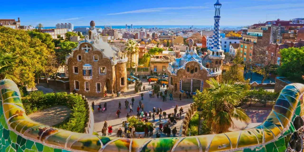 A vibrant view of Park Güell in Barcelona, with its iconic mosaic-covered benches and whimsical buildings. This is the perfect place to start your trein naar Barcelona adventure.