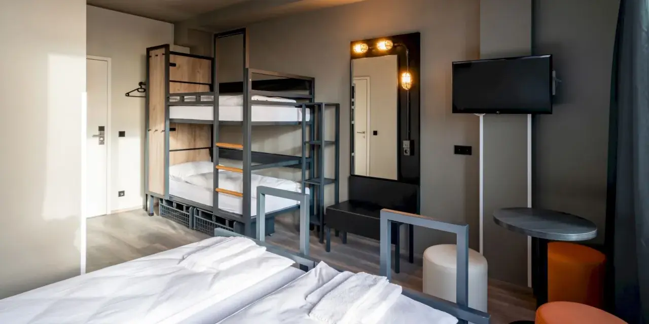 Pokój wieloosobowy w hotelu a&o Warszawa z łóżkami piętrowymi, dwoma łóżkami pojedynczymi i telewizorem.