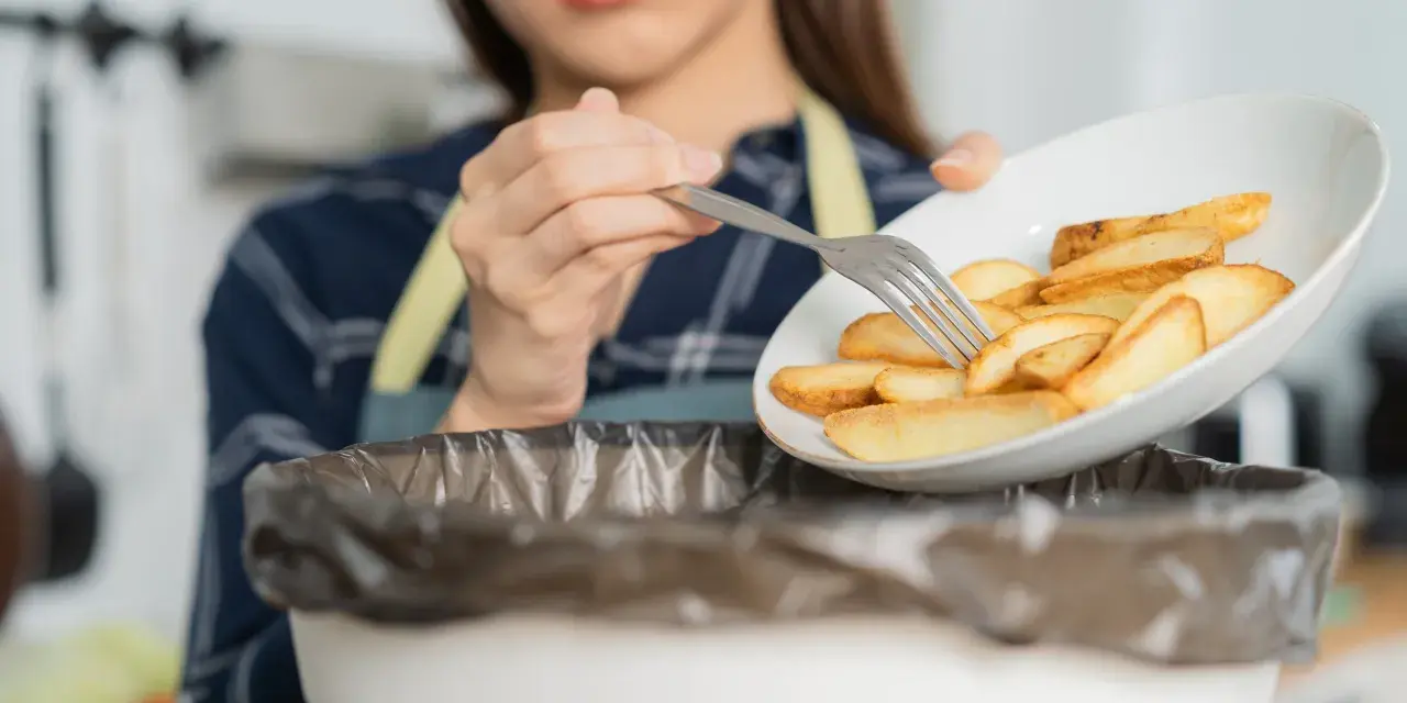 Kobieta wyrzuca frytki, zaczynając drogę do tego, jak obniżyć cholesterol bez leków. Zdrowa dieta to klucz.