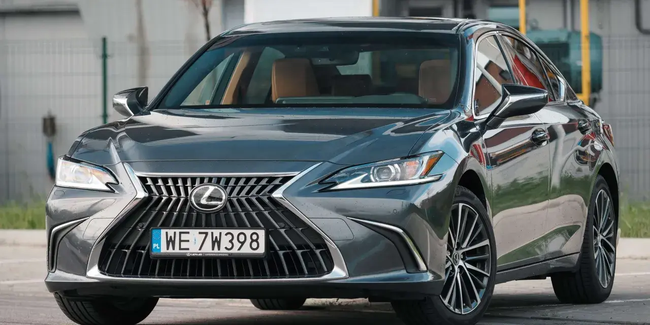 Elegancki, ciemnoszary Lexus 300h z brązowym wnętrzem stoi na parkingu.