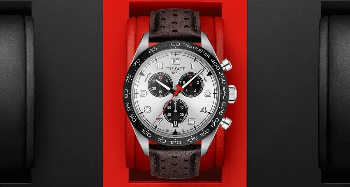 Zegarek Tissot z czarnym bezelem, na którym widnieje skala tachymetru. Skórzany pasek dodaje mu elegancji.
