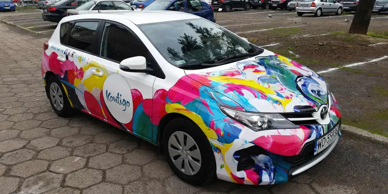 Kolorowe oklejone samochody z logo "Koutigo" na parkingu.