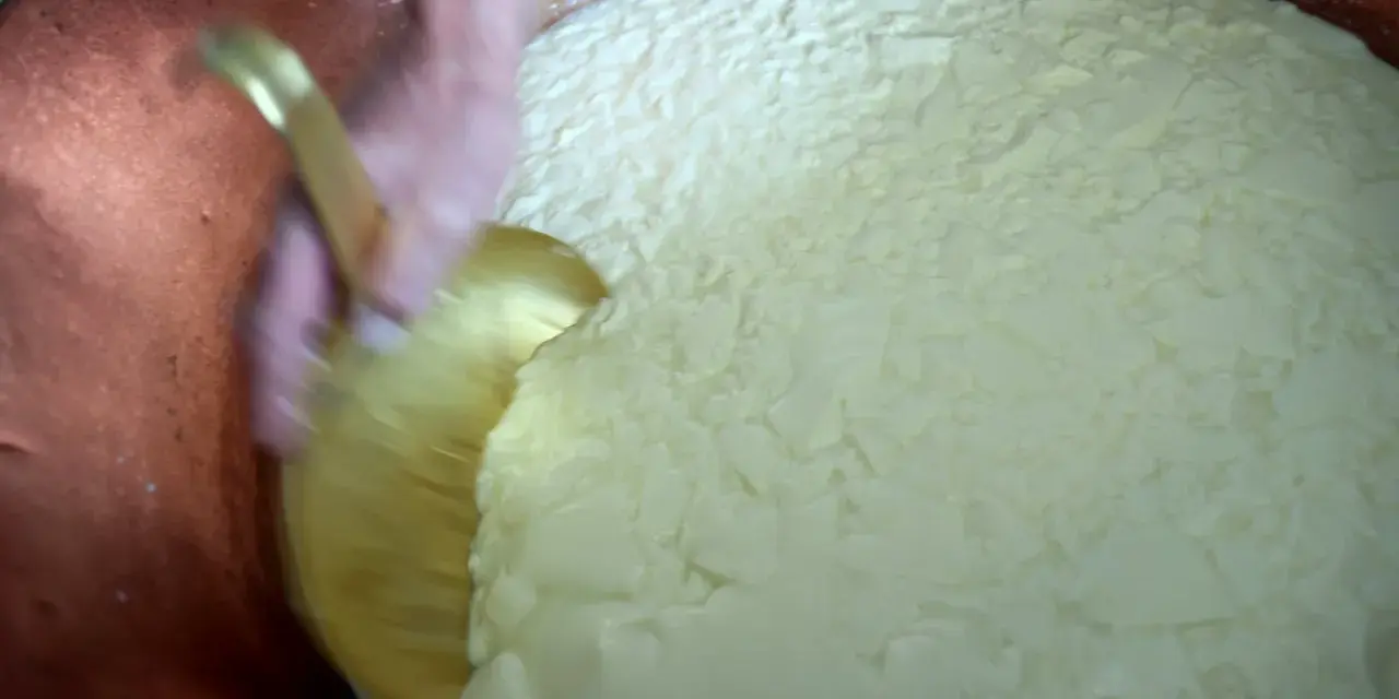 Mélange du caillé dans une cuve en cuivre, étape clé après la traite des vaches pour la fabrication du fromage.