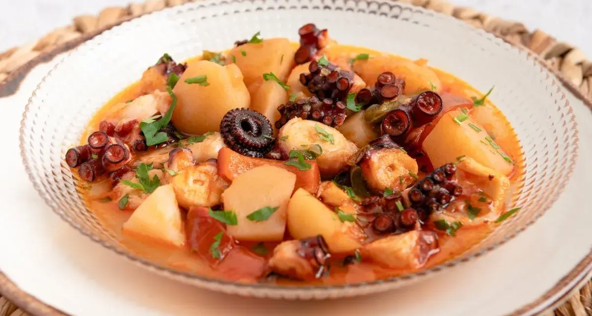 Un delicioso pulpo a la mugardesa, con patatas tiernas y un sofrito sabroso, adornado con perejil fresco.