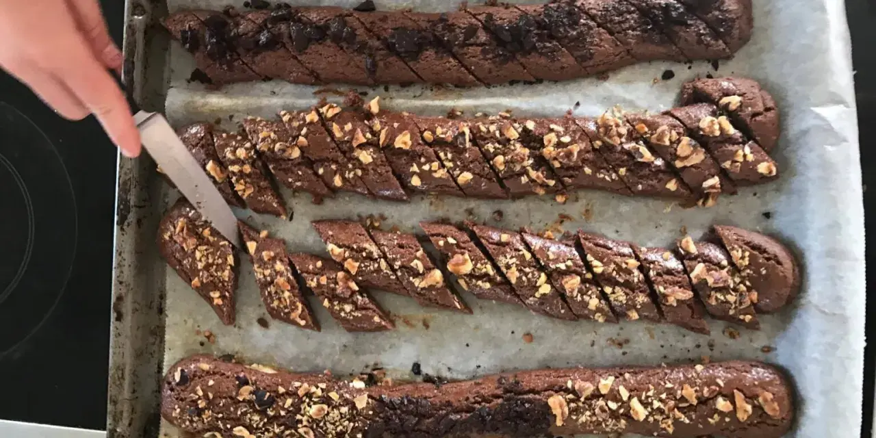 Chokladsnittar recept: Nybakade chokladkakor med nötter och chokladbitar skärs upp på en plåt.