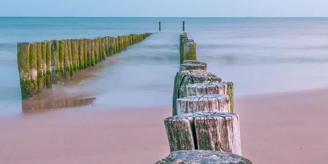 Drewniane pale tworzą ścieżkę wzdłuż plaży, prowadzącą w stronę morza. To idealne miejsce na spacer, odkrywając kąty rybackie trasę.
